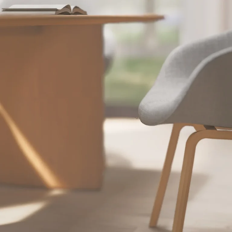 Heller, reduzierter Essplatz mit Holztisch, ergonomischem Stuhl und natürlichem Licht. Gestaltung, die Ruhe, Komfort und Konzentration im Alltag unterstützt. Holztisch mit offenem Buch und ergonomischem Stuhl – ruhiger Platz für komfortables, vitales Wohnen